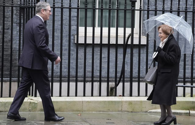 Prime Minister Sir Keir Starmer greets Holocaust survivor Mala Tribich, carrying an umbrella, in Downing Street