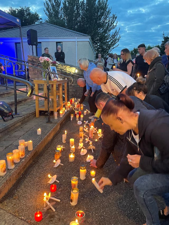 People lay candles at a vigil for the boys