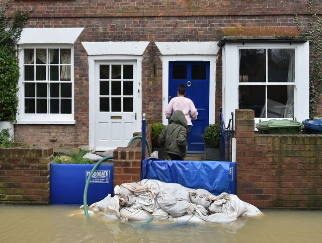 A woman and child enter a flood-hit cottage