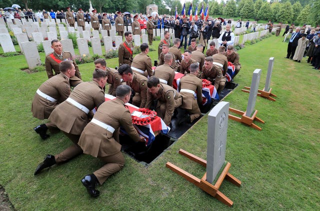 Soldiers carry the coffins of two young privates and an unknown soldier, who fought during the First World War, during a burial service at Hermies Hill British Cemetery, near Albert, France