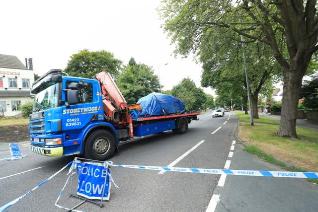 A vehicle covered in a tarpaulin is removed from the scene in Bradford