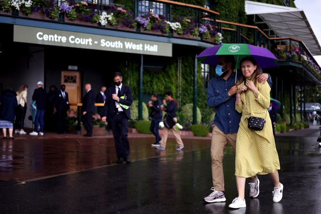 Fans sheltering from rain on day eight at Wimbledon