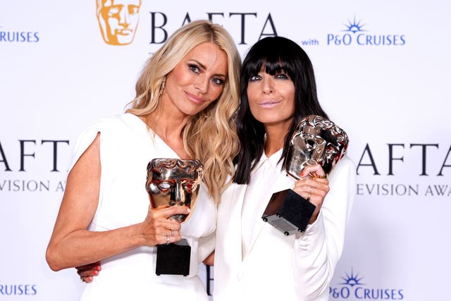 Tess Daly and Claudia Winkleman posing together in white outfits each holding a Bafta award