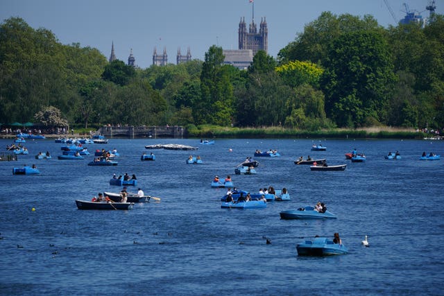 People ride pedalos on the Serpentine in Hyde Park, London