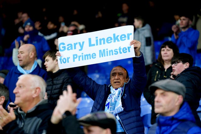 A Manchester City fan holds up a sign reading