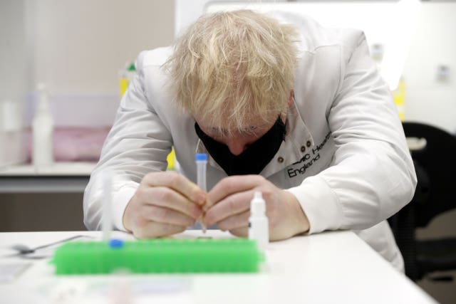 Prime Minister Boris Johnson looks at samples in the Lateral Flow Testing Laboratory during a visit to Public Health England Porton Down