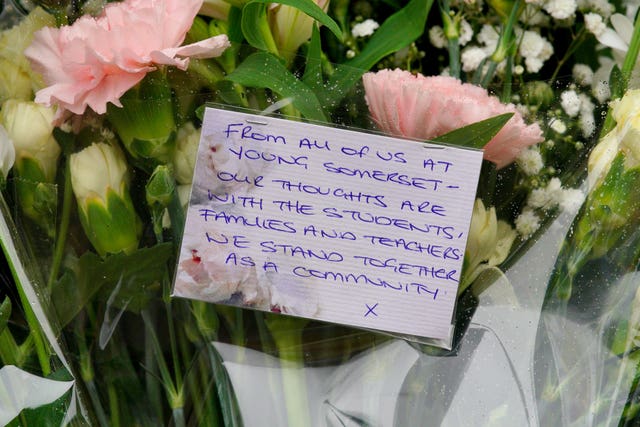 A note left on a bunch of flowers among the floral tributes