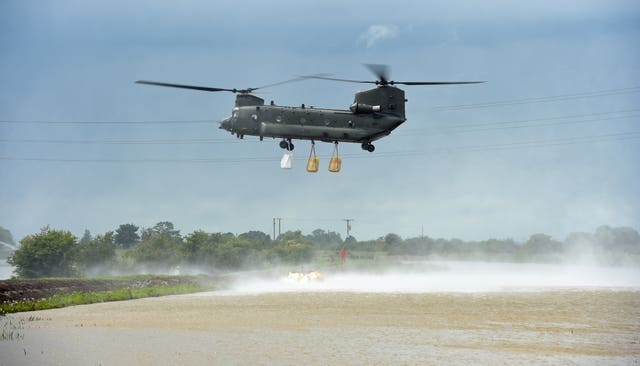 An RAF Chinook helicopter delivers sandbags to plug a gap where the River Steeping burst its banks near Wainfleet All Saints, in Lincolnshire