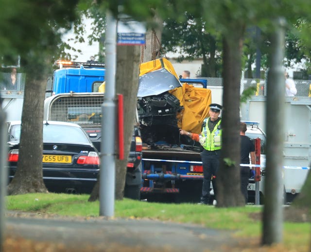 A car covered by a tarpaulin is removed from the scene in Bradford