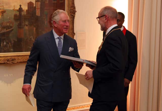 The Prince of Wales is presented with a book during his viewing of the exhibition (Andrew Matthews/PA)