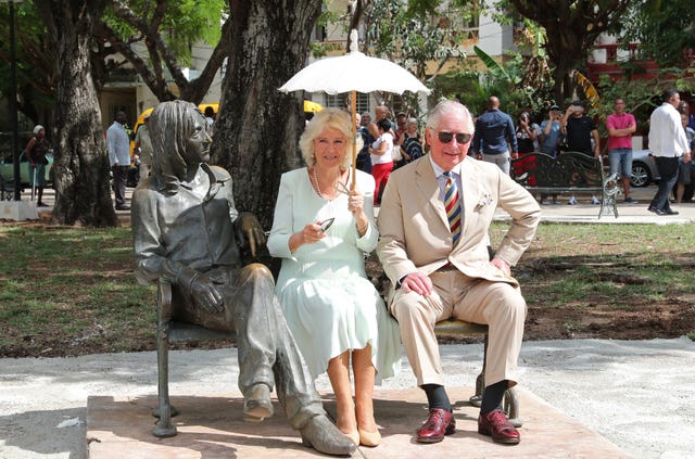 The Prince of Wales and the Duchess of Cornwall sit on the John Lennon memorial bench in John Lennon Square in Havana, Cuba