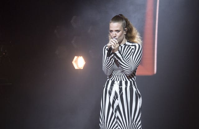Jess Glynne performing, wearing a black and white striped outfit