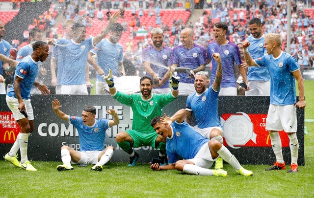 The trophy falls off the plinth as Manchester City players celebrate at Wembley