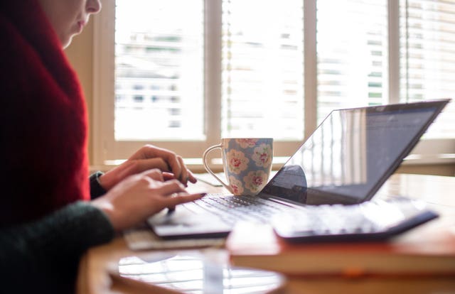 A woman using a laptop on a dining room table