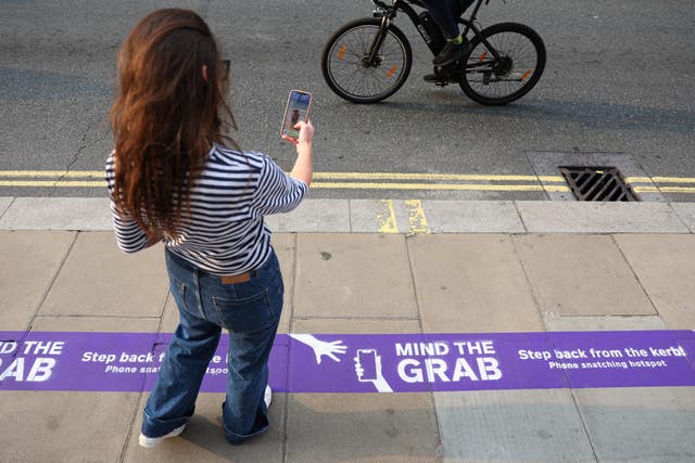 A woman next to Currys' Mind The Grab purple line in London's Oxford Street