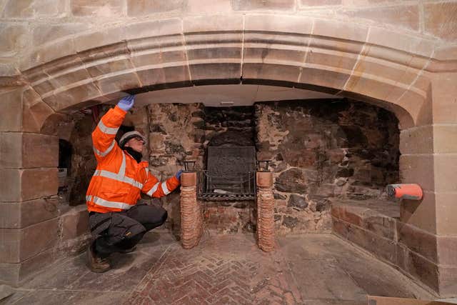 A workman works on a fireplace as restoration work is carried out on Lindisfarne Castle
