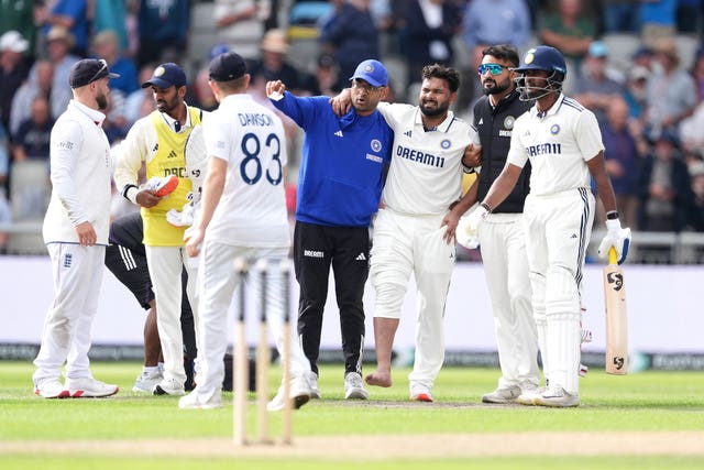 Rishabh Pant (centre right) is helped off the field