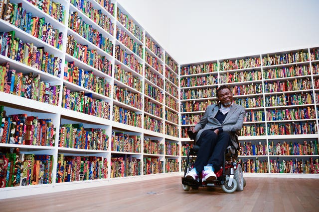 Yinka Shonibare with his work, The British Library, at Tate Modern, London (Rebecca Brown/PA)