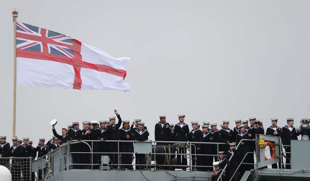 Members of the crew wave as HMS Ocean, the Royal Navy's fleet flagship, makes her way to HM Naval Base Devonport, Plymouth (Andrew Matthews/PA)after six months on operations.