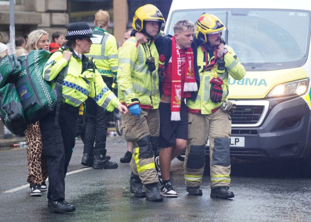 A man is helped from the scene by firefighters after a car crashed into a crowd in Liverpool