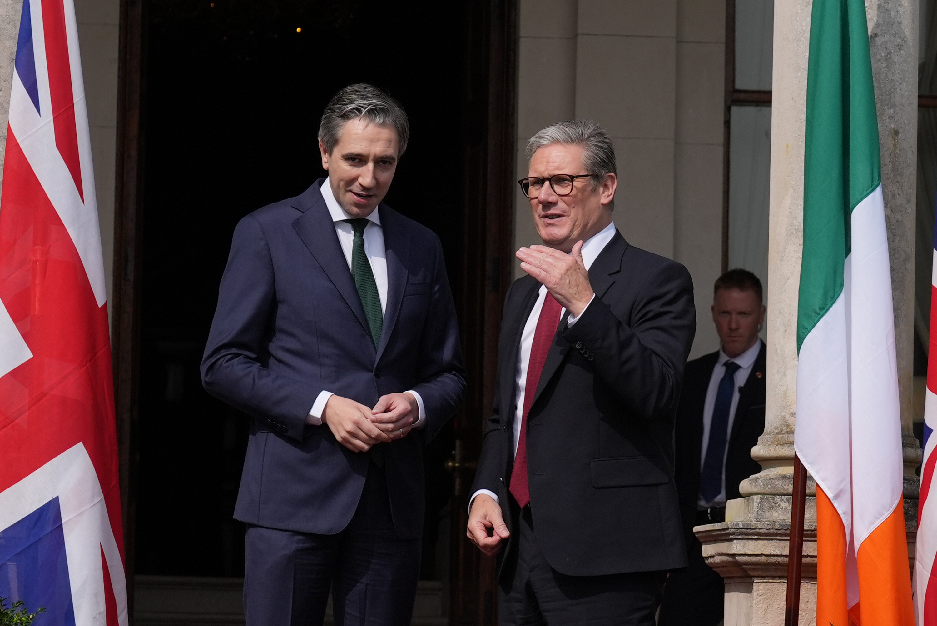 Simon Harris and Sir Keir Starmer standing between a Union and Irish flag outside Farmleigh House