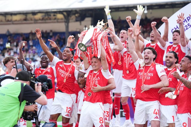 Martin Odegaard lifts the Premier League trophy surrounded by his Arsenal team-mates