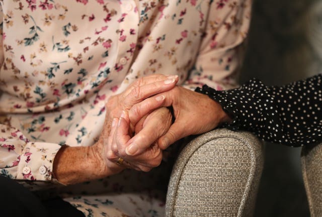 An elderly person holding hands