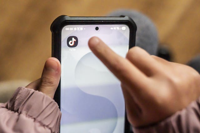 A young person's hands using te TikTok app on a smartphone
