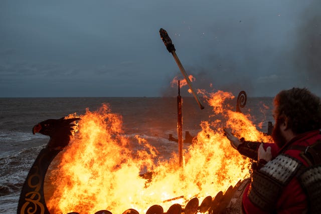 A longboat burns on the beach