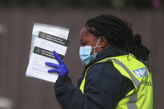 Staff hand out self-test kits at a coronavirus testing centre in Bolton