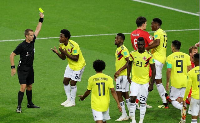 Colombia’s Carlos Sanchez, second left, is booked after conceding a penalty against England