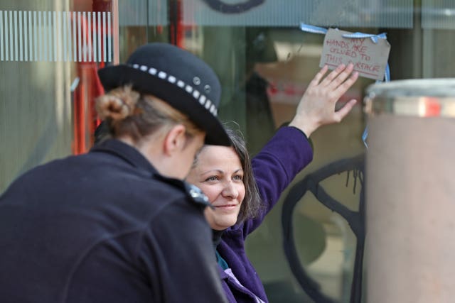 Police speak to a demonstrator who glued herself to the front of the Shell building on the Southbank