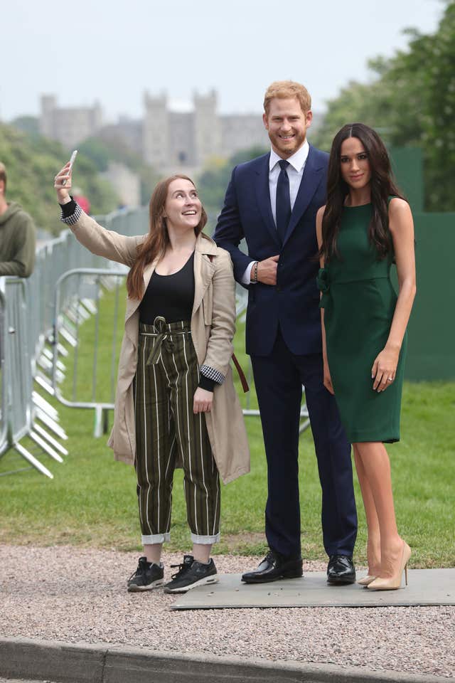 A royal fan takes a selfie with Madame Tussauds’ wax figures of Prince Harry and Meghan Markle (Jonathan Brady/PA)