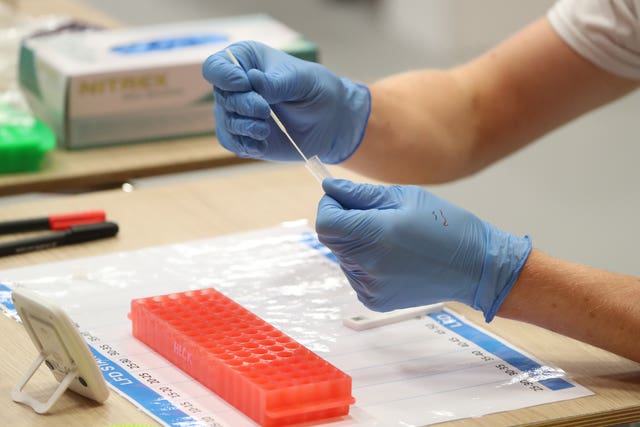 People carry out asymptomatic testing using lateral flow antigen at a test centre