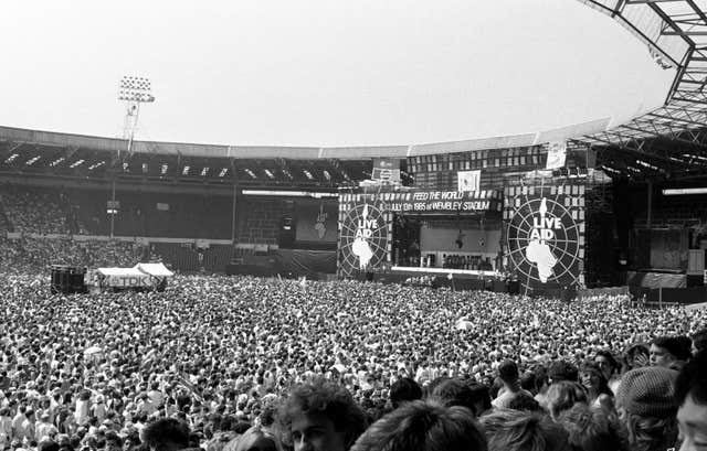 Black and white image of the crowd and stage of the Live Aid Concert at Wembley Stadium in 1985