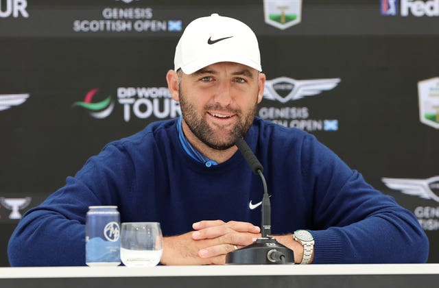Scottie Scheffler leans on the desk in a press conference