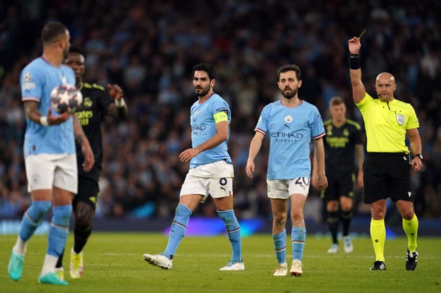 Manchester City’s Ilkay Gundogan, centre, is shown a yellow card by referee Szymon Marciniak, right, during the Champions League semi-final second leg against Real Madrid