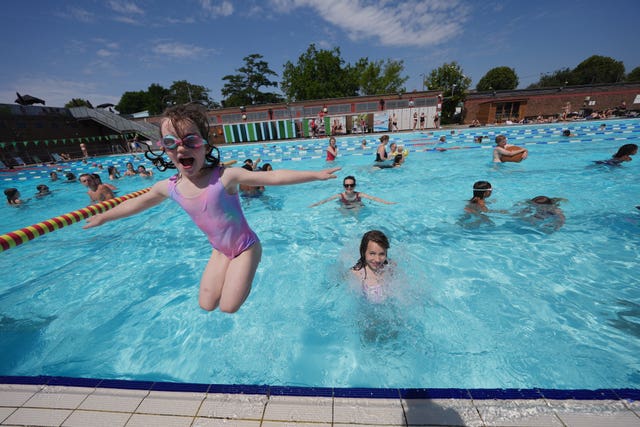 Sisters Aurelia (left) and Meriel Dawson leap into the water at Charlton Lido in south east London