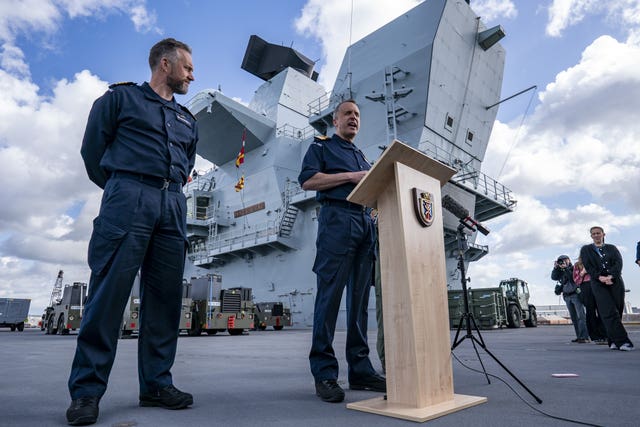 Commodore James Blackmore, the commander of the Carrier Strike Group, centre, speaks to assembled media as Captain Will Blackett looks on