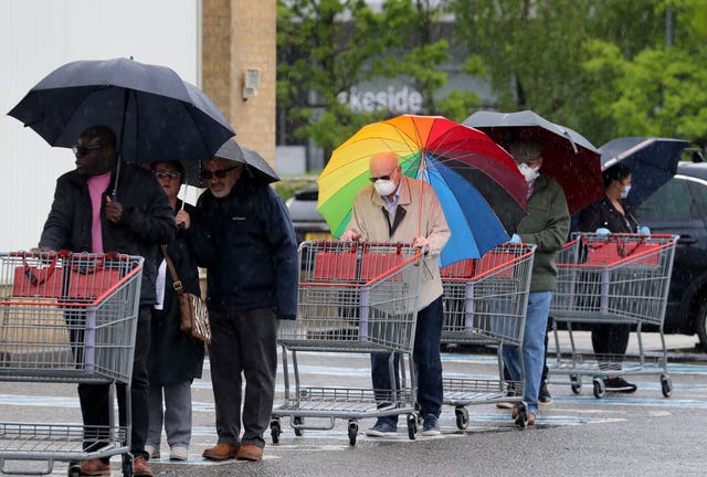 A shopper outside Costco in Thurrock carried a rainbow umbrella during Tuesday's silence for fallen key workers