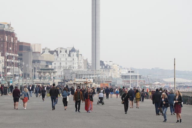People walk along the promenade at Brighton, East Sussex