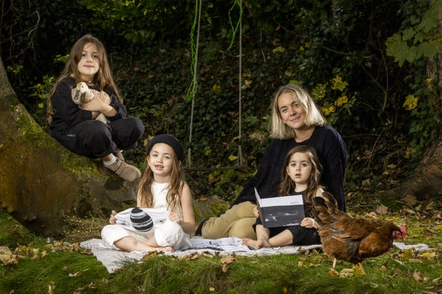 Ciara Tinney with her three children, seated on grass by woodland