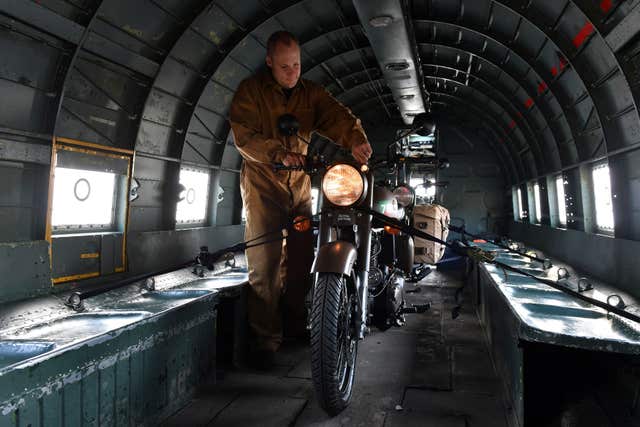 Engineer Ed Cobb secures two limited edition Royal Enfield 'Classic 500cc Pegasus' motorbikes into the back of a Dakota C-47 transport plane before they are unveiled at Imperial War Museum Duxford (Joe Giddens/PA)