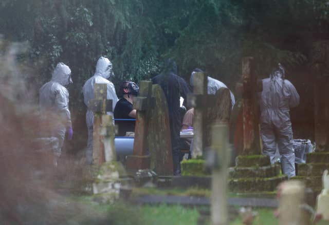 Forensic officers in gas masks at the London Road cemetery (PA)