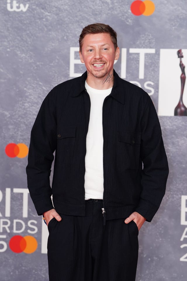 Professor Green smiling while posing for photos at a red carpet event