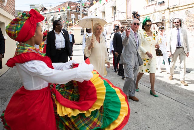 The Prince of Wales and the Duchess of Cornwall watch dancers during a walkabout through the streets of St George’s