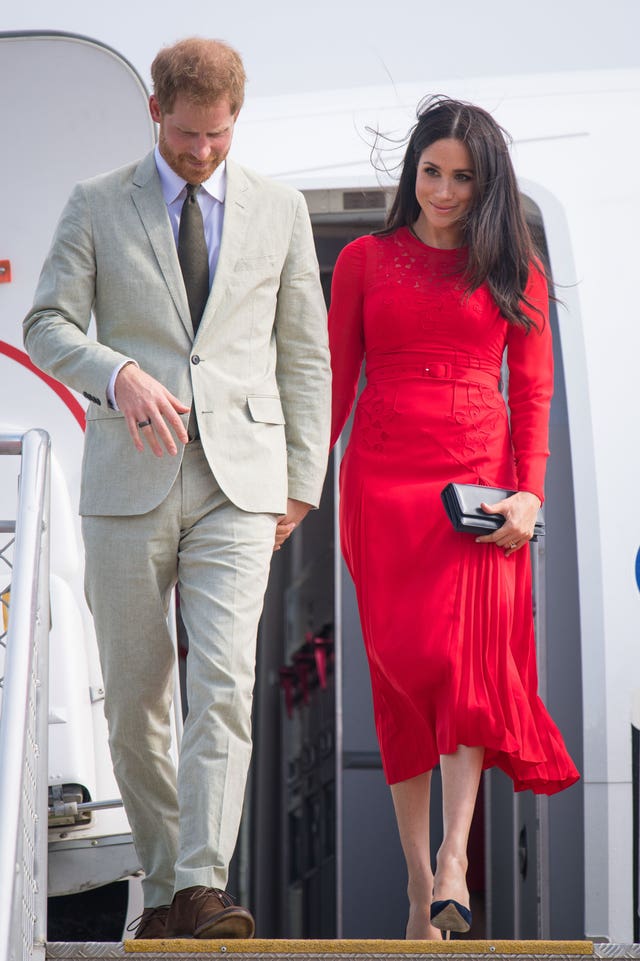 The Duke and Duchess of Sussex arriving at Fua'amotu Airport, Tonga, with Meghan wearing a £345 red outfit by London fashion brand Self-Portrait.