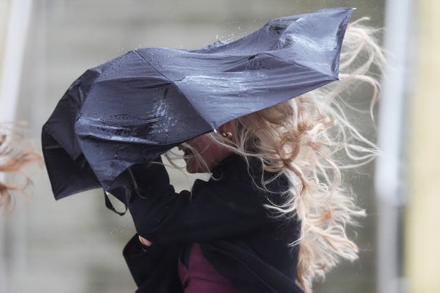 A racegoer struggles with an umbrella at Cheltenham Racecourse