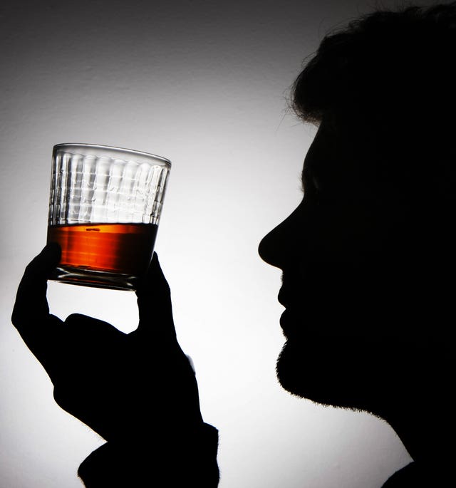 Silhouette of a man holding up a dram of whisky