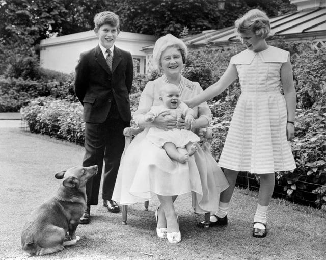 Prince Andrew smiles on the lap of his grandmother, the Queen Mother, as his brother, Prince Charles, and sister, Princess Anne, look on, in the garden of Clarence House, London (PA)